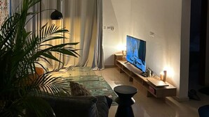 A modern living room with a flat-screen TV, a glass coffee table, and a sofa.