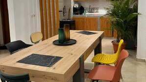 A modern dining area with a wooden table, black and yellow chairs, and a potted plant.