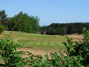 A golf course with a clear sky, trees, and a few people. - 5 Star Holiday Home in Ebeltoft (Ebeltoft)