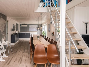Une cuisine moderne avec un coin repas, un plancher en bois et un escalier.