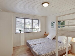 A room with a bunk bed, a window with blinds, a small table, and a wall-mounted shelf. - 5 Star Holiday Home in Ebeltoft (Ebeltoft)