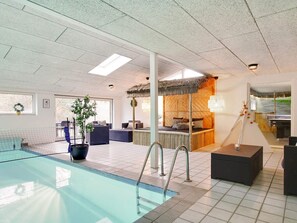 A hotel room with a pool, a thatched-roof bed, and a dining area with a view. - 5 Star Holiday Home in Ebeltoft (Ebeltoft)