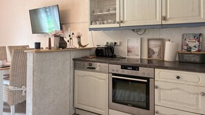 Une cuisine équipée d’un lave-vaisselle Bosch, d’un four Siemens et d’un téléviseur à écran plat fixé au mur.