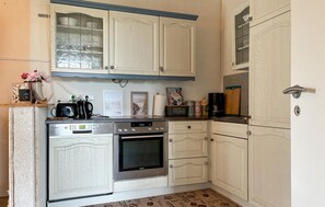 A kitchen with white cabinetry, a Bosch stove, a Siemens oven, and various kitchen items on the counter.