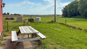 Une table de pique-nique dans un champ verdoyant, avec une grange en arrière-plan.
