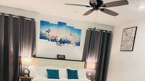 Een hotelkamer met een bed, twee nachtkastjes, een plafondventilator en kunst aan de muur.