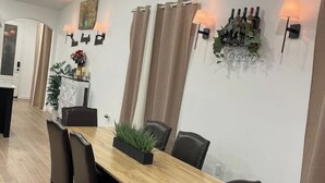 Een eetgedeelte met een houten tafel en stoelen, een planten decoratie en wandlampen.