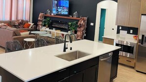 Een moderne keuken met een centraal eiland, zwarte kastjes en roestvrijstalen apparatuur.