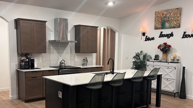 Een moderne keuken met een centraal eiland, barstoelen en een koffieapparaat.
