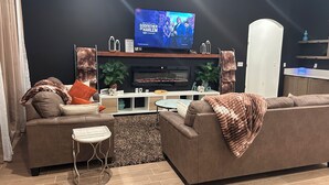 Un soggiorno moderno con una TV a schermo piatto, due divani, un tavolino da caffè e un piccolo tavolino laterale.