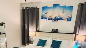 Una camera da letto con un letto, un comodino, una lampada e un quadro di una farfalla appeso al muro.