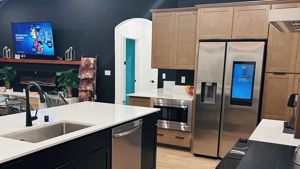 Una cucina moderna con isola centrale, elettrodomestici in acciaio inossidabile e un televisore a schermo piatto appeso al muro.