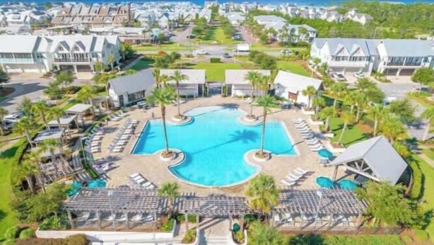 A resort with a central swimming pool, multiple lounge areas, and a view of surrounding buildings.
