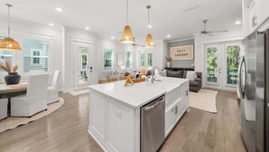 A modern kitchen with a central island, pendant lighting, and a view of the outdoors.