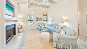 A living room with a sectional sofa, a fireplace, and a ceiling fan. - Salt & Sunset by Stay on 30a (Watercolor)