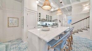 A spacious kitchen with white cabinetry, a large island, and wicker bar stools. - Salt & Sunset by Stay on 30a (Watercolor)