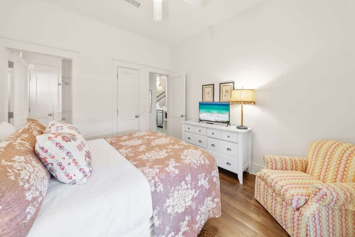 A bedroom with a bed, a dresser, a TV, and a chair.