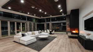 Ein geräumiges Wohnzimmer mit einem Ecksofa, einem Kamin und einem großen Fernseher.