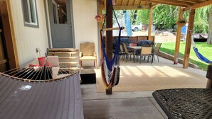 Eine überdachte Terrasse mit Hängematte, Sitzgelegenheiten im Freien und einer Tür zum Innenbereich.