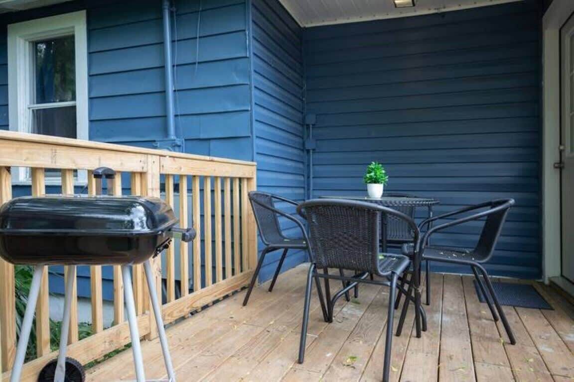Eine überdachte Terrasse mit Grill, Stühlen und einem kleinen Tisch.