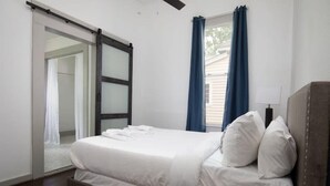 A bedroom with a bed, a sliding door, and a window with curtains. - Division Ave East Lake Update (Birmingham)
