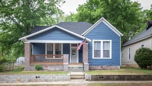 A single-story house with a front porch, a brick foundation, and a blue siding exterior. - Division Ave East Lake Update (Birmingham)