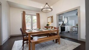 A dining area with a wooden table, benches, and a chandelier. - Division Ave East Lake Update (Birmingham)