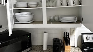 A kitchen with white cabinets, a granite countertop, a microwave, a toaster, and a sink. - 12th Ave The Bricks - Unit 5 (Birmingham)