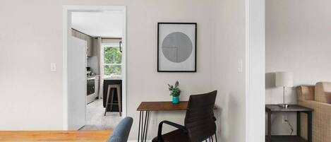 A modern kitchen with white cabinets, a wooden countertop, and a view into the dining area.