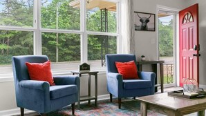 A room with two blue armchairs, a small wooden table, and a colorful rug. - Dugan Ave Dugout - Unit A (Birmingham)