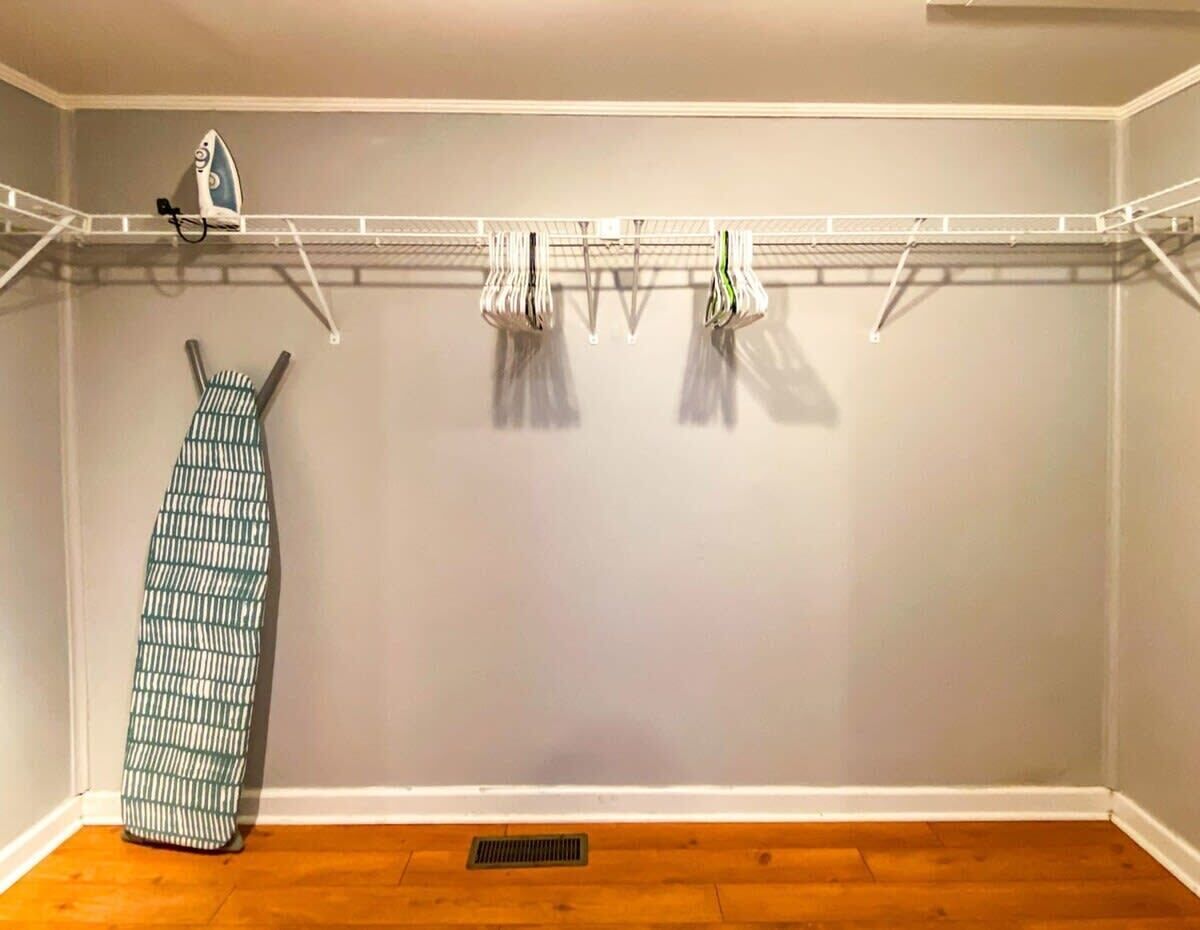 A laundry area with a drying rack, hanging clothes, and a folded garment.