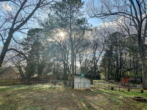 A fenced yard with a small shed, a wooden play structure, and a house in the background. - Cardinal Aerie (Madison)