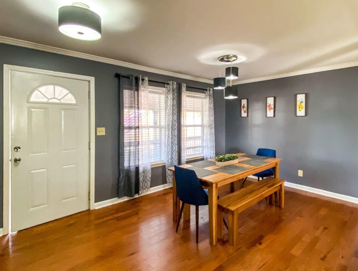 A dining area with a wooden table and chairs, a white door, and grey walls.