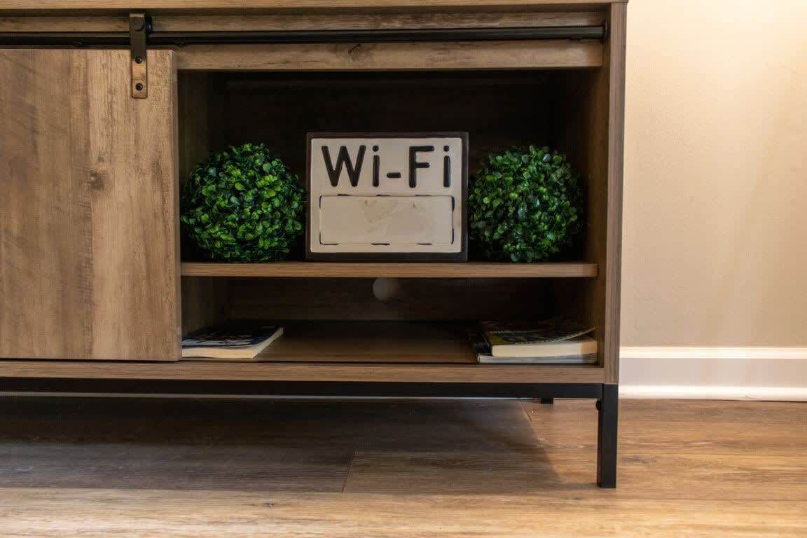 A wooden cabinet with a 'Wi-Fi' sign, two green plants, and a book on the shelf.