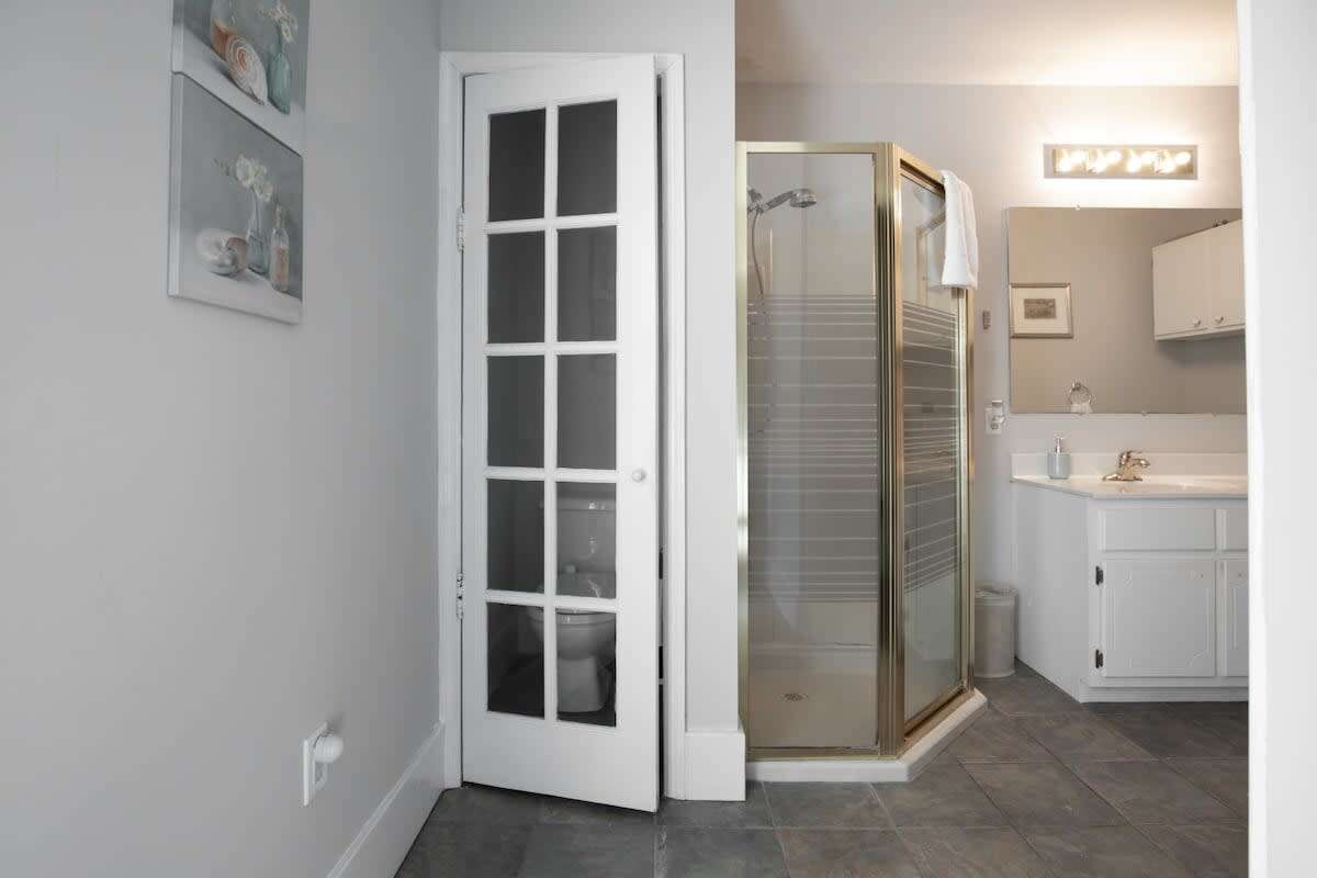 A bathroom with a glass shower enclosure, a white sink, and a toilet.