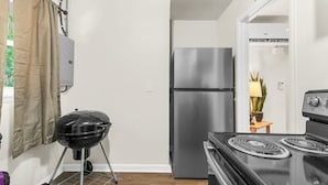 Eine kleine Küche mit einem Edelstahlkühlschrank, einem Gasherd und einem tragbaren Grill.