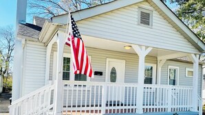 Une maison blanche avec un porche et un drapeau américain.