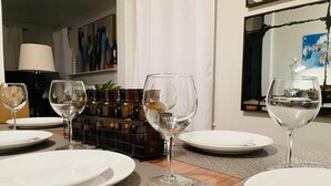 Un coin repas avec une table dressée, des verres à vin et un porte-bouteilles en arrière-plan.