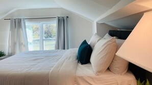 Une chambre à coucher avec un grand lit, une lampe de chevet et une fenêtre avec des rideaux.