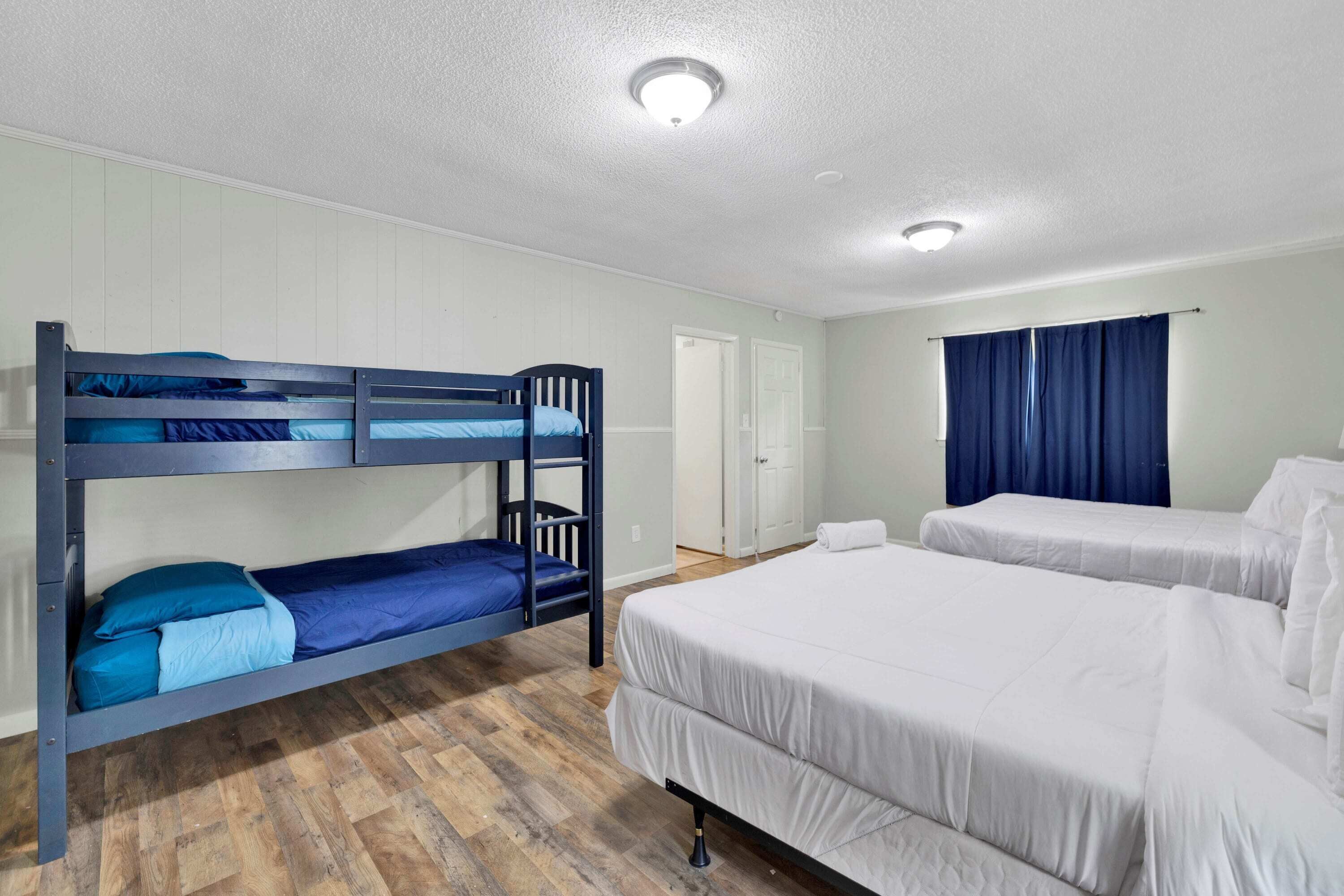 A room with bunk beds, a large bed, and a door.