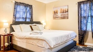 A neatly made bed with white linens, a headboard, and two bedside lamps.