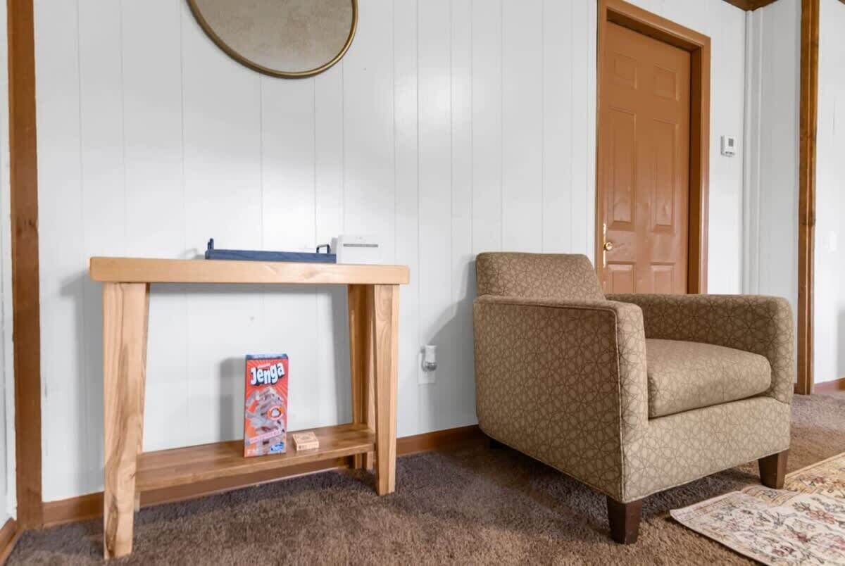 A room with a wooden console table, a patterned armchair, and a door.