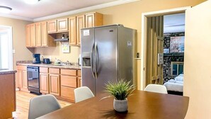 Una cocina moderna con armarios de madera, un refrigerador de acero inoxidable y una mesa de comedor con sillas.