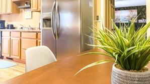 Una cocina moderna con armarios de madera, un refrigerador de acero inoxidable y una planta en maceta sobre la encimera.