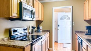 Una cocina con armarios de madera, estufa de acero inoxidable y microondas.