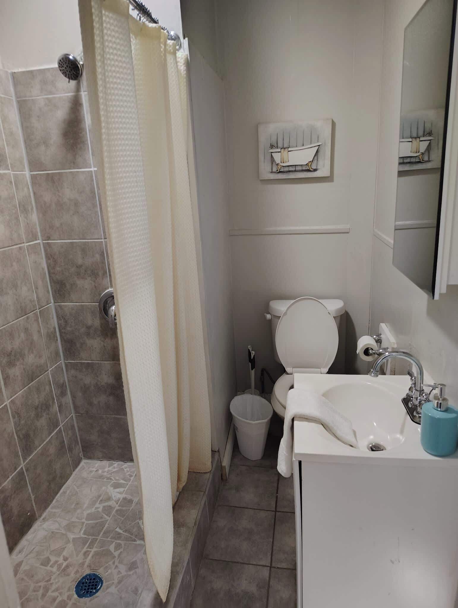 Ein Badezimmer mit Dusche, Toilette, Waschbecken und einem Handtuch an der Wand.