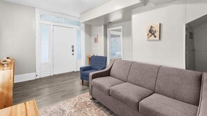 A living room with a grey sofa, a blue armchair, and a wooden coffee table. - 29th Street Ensley Heights Hideaway 1 (Birmingham)