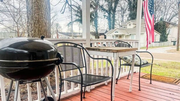 A covered outdoor area with a grill, metal chairs, and a small table.
