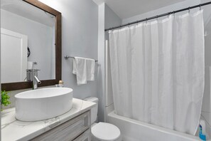 A bathroom with a white sink, a toilet, a bathtub, and a shower curtain.