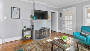 A living room with a fireplace, a blue armchair, and a patterned rug. - 49th Terrace Haven (Birmingham)